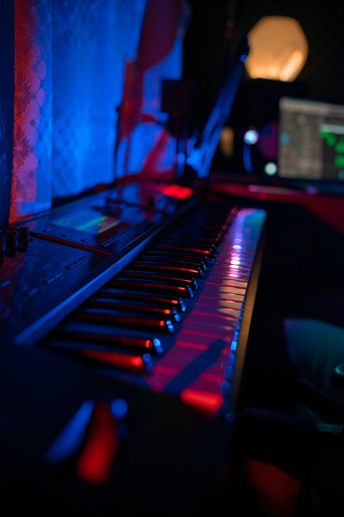 Crafting Captivating Headlines: Your awesome post title goes here Moody music studio featuring a synthesizer keyboard and computer screen with neon lighting.